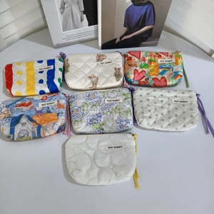 Sept mini pochettes matelassées aux motifs floraux et animaux disposées sur fond blanc