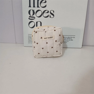 Detailed close-up of quilted heart pattern and May Rabbit label on the beige makeup bag