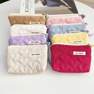 Flat lay of quilted heart mini pouches in various colors with zipper on white table
