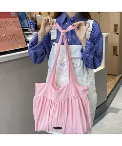 Detail of pink pleated cotton tote bag with knot handle and Romance woven label