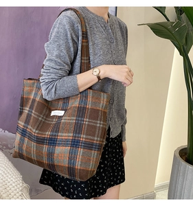 Détail d'un grand sac cabas en laine à carreaux vintage porté par un mannequin
