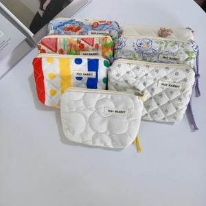 Détails de mini trousses de maquillage matelassées aux motifs floraux et rayures