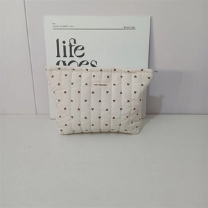 Detailed view of quilted cotton makeup bag with heart patterns and May Rabbit logo tag