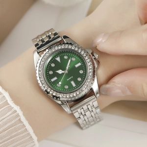 Detailansicht einer silbernen Uhr mit grünem Zifferblatt und glitzernder Lünette