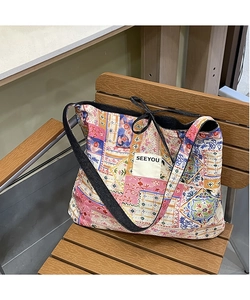 Detail of colorful patchwork canvas tote bag featuring floral patterns and SEEYOU label