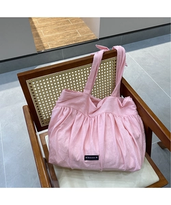 Detail of pink pleated linen tote bag with Romance label on a vintage chair