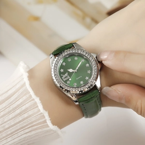 Gros plan d'une montre à quartz avec cadran vert émeraude et lunette en strass sur cuir