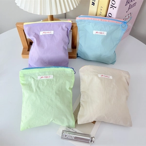 Set of four pastel macaron cosmetic pouches in purple, blue, mint green, and beige colors