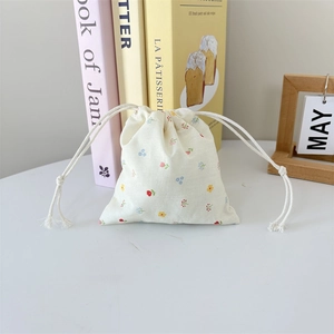 Detail of floral cotton drawstring pouch with soft fringe strings on a desk background
