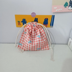 Detail of red and white checkered cotton pouch with blue bow prints and drawstring