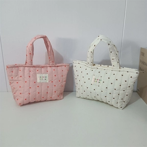 Detailed view of quilted cotton handbags with heart patterns in pink and white