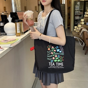 Détail du sac cabas en toile noire avec broderie florale et cordon blanc réglable