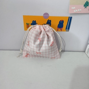 Detail view of pink bow pattern and checkered fabric on drawstring cotton pouch
