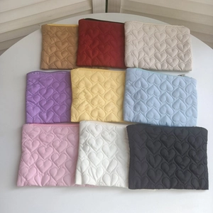 Set aus neun gesteppten Herz-Kosmetiktaschen in leuchtenden Farben auf dem Tisch