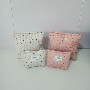 Close-up of quilted heart pattern pouches in pink and cream with vertical stitching detail