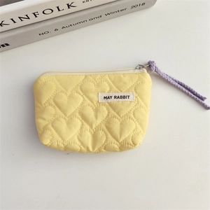 Detailed view of yellow heart quilted makeup bag with purple zipper pull and woven label