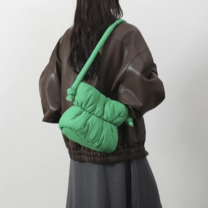 Bolso bandolera acolchado verde brillante con detalle de nudo mostrado en modelo