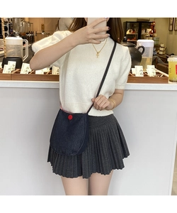 Dark blue denim crossbody bag with red decorative button detail shown on model