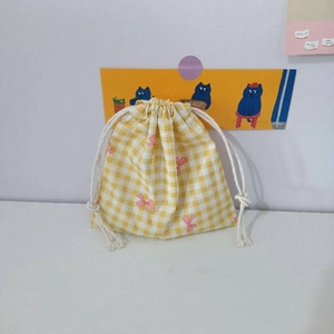 Detail of yellow checkered cotton drawstring bag with pink bow patterns and dual closure