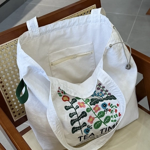 Détail de la broderie florale et de la fermeture à cordon du grand sac en toile