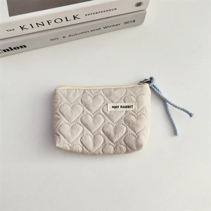 Detail of quilted heart pattern fabric pouch with zipper puller and brand tag