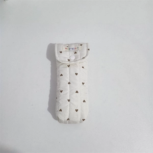 Detail of quilted cotton pouch with heart patterns, featuring a snap button and label