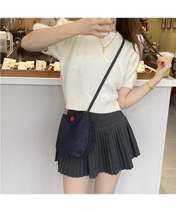 Lifestyle shot of a dark denim crossbody bag with a red button on a casual outfit
