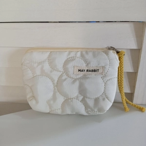 Vue détaillée du petit porte-monnaie matelassé blanc avec cordon jaune et fermeture éclair