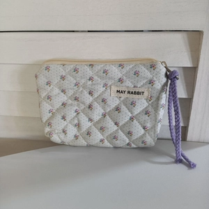 Détail de la mini pochette matelassée à fleurs avec étiquette May Rabbit et dragonne violette