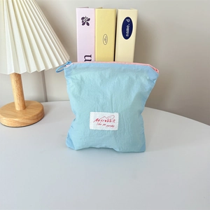 Close-up of a light blue macaron mini cosmetic bag with pink zipper and branded tag