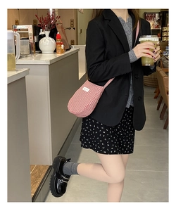 Street style shot of red gingham small crossbody bag paired with a black blazer and loafers
