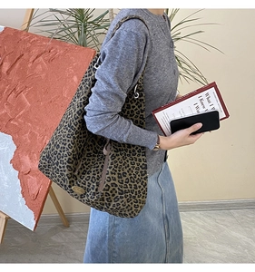 Detail shot of leopard print hobo tote bag with gold logo plaque and shoulder drape