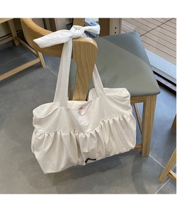 Detail of creamy white canvas tote bag with pleat textures and large bow handle design