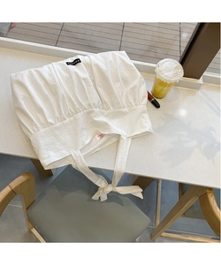 Detailed view of white pleated cotton vest with drawstring tie on a cafe table