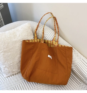 Detail of orange canvas tote bag with yellow gingham lining and minimalist front pocket label