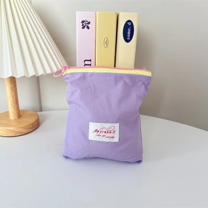 Detail of purple nylon makeup pouch with colorful zipper and decorative woven label