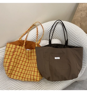 Detail of a plaid yellow tote bag and brown bag with leopard print lining on a sofa