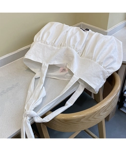 Detail of white cotton linen tote bag with ruched texture and adjustable tie straps