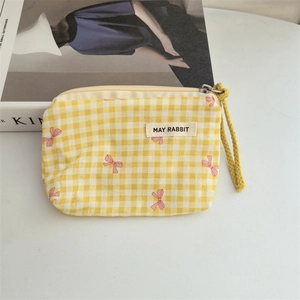 Close-up of yellow checkered cotton coin purse with pink bow pattern and wrist strap
