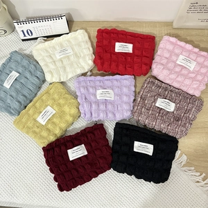 Bubble textured makeup bags in multiple colors organized on a rustic wooden table