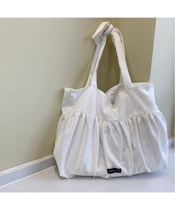 Detail of white cotton tote bag with pleated design and knotted wide shoulder straps