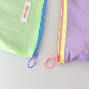 Close-up of macaron-colored mini pouches featuring contrast zippers and brand labels