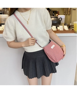 Detail of red gingham crossbody bag with half-moon design and woven shoulder strap