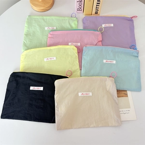Detail of colorful macaron mini cosmetic pouches with round ring zipper pulls and woven label
