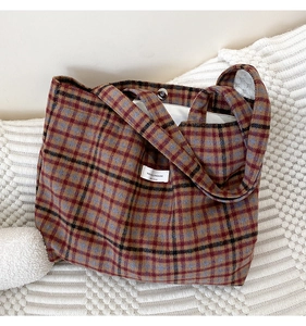 Détail du sac cabas en laine à carreaux avec texture vintage et fermoir magnétique