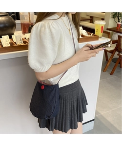 Close-up of denim crossbody bag with red button detail and checkered lining in cafe