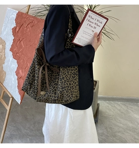 Close-up of leopard print tote bag with drawstring side and gold metal logo plaque