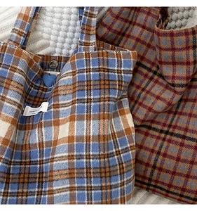 Gros plan sur le sac cabas en laine à carreaux montrant le tissu épais et le bouton pression