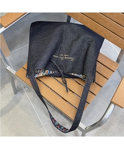 Detail of denim tote bag with golden Fantasy Romance embroidery and boho lining