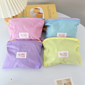 Macro detail of four macaron colored nylon storage bags with red and white logo patches